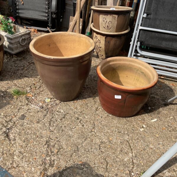 Pair of glazed terracotta garden planters in a garden setting.