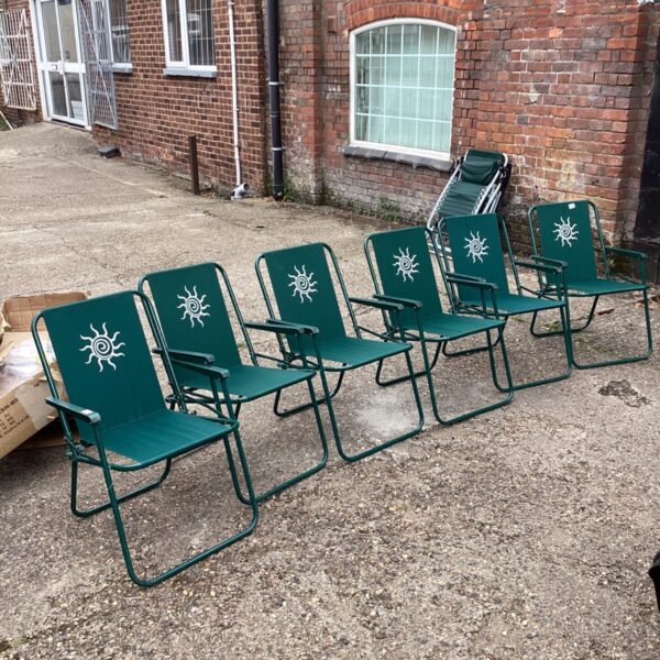 Set of six green folding garden chairs in a garden setting.