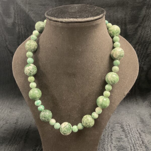 Close-up of a beautiful green jade necklace with a silver clasp.