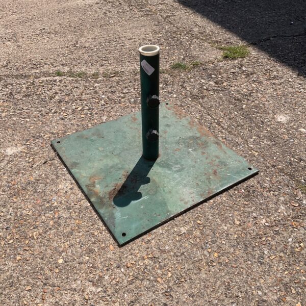 Green metal umbrella stand for outdoor patio use.