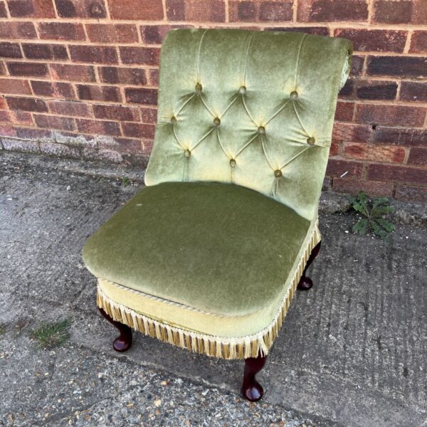 Vintage green velvet nursing chair with button-back detail.