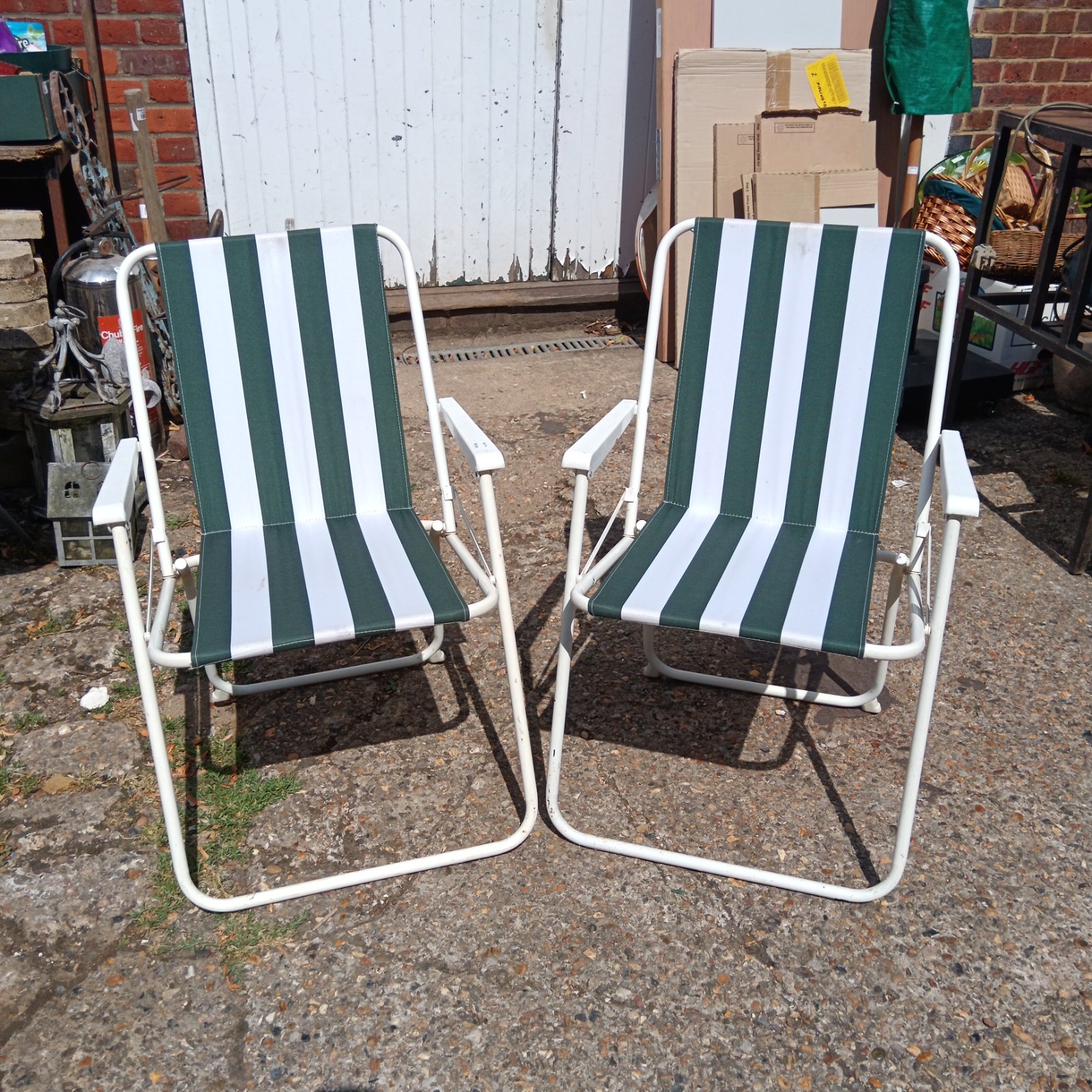 Pair of green and white striped folding garden chairs in a garden.
