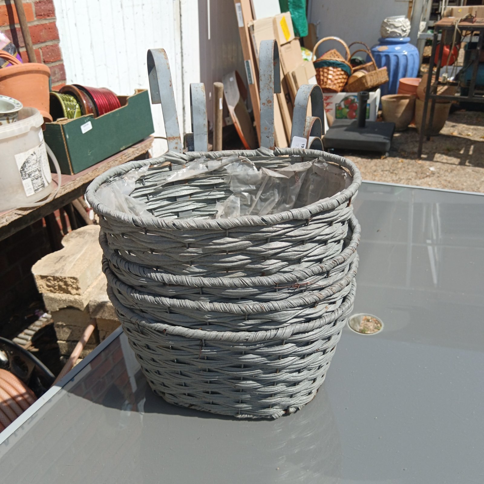 Set of four grey wicker basket planters for garden use.