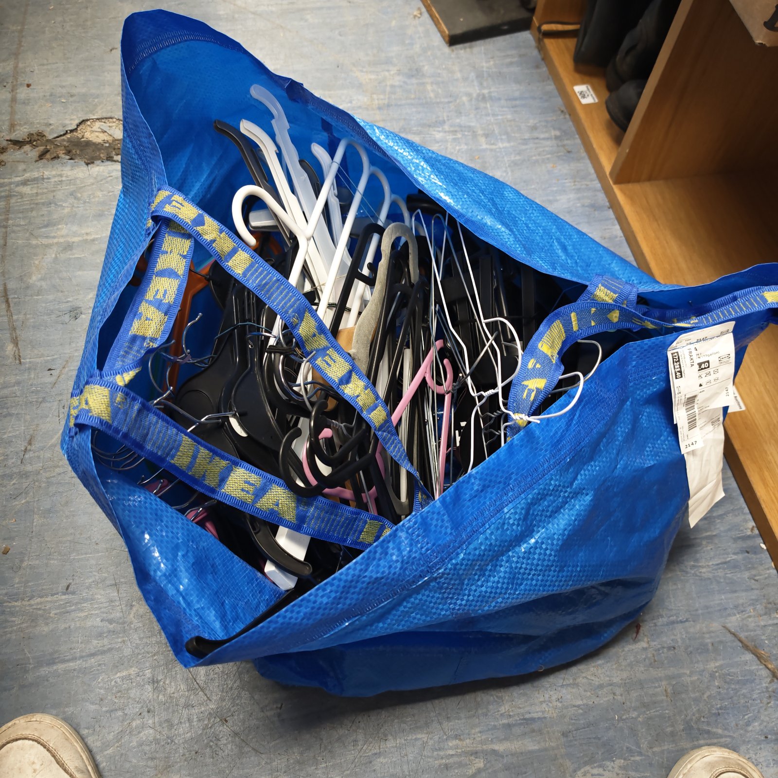 Blue IKEA bag filled with a lot of plastic clothes hangers.
