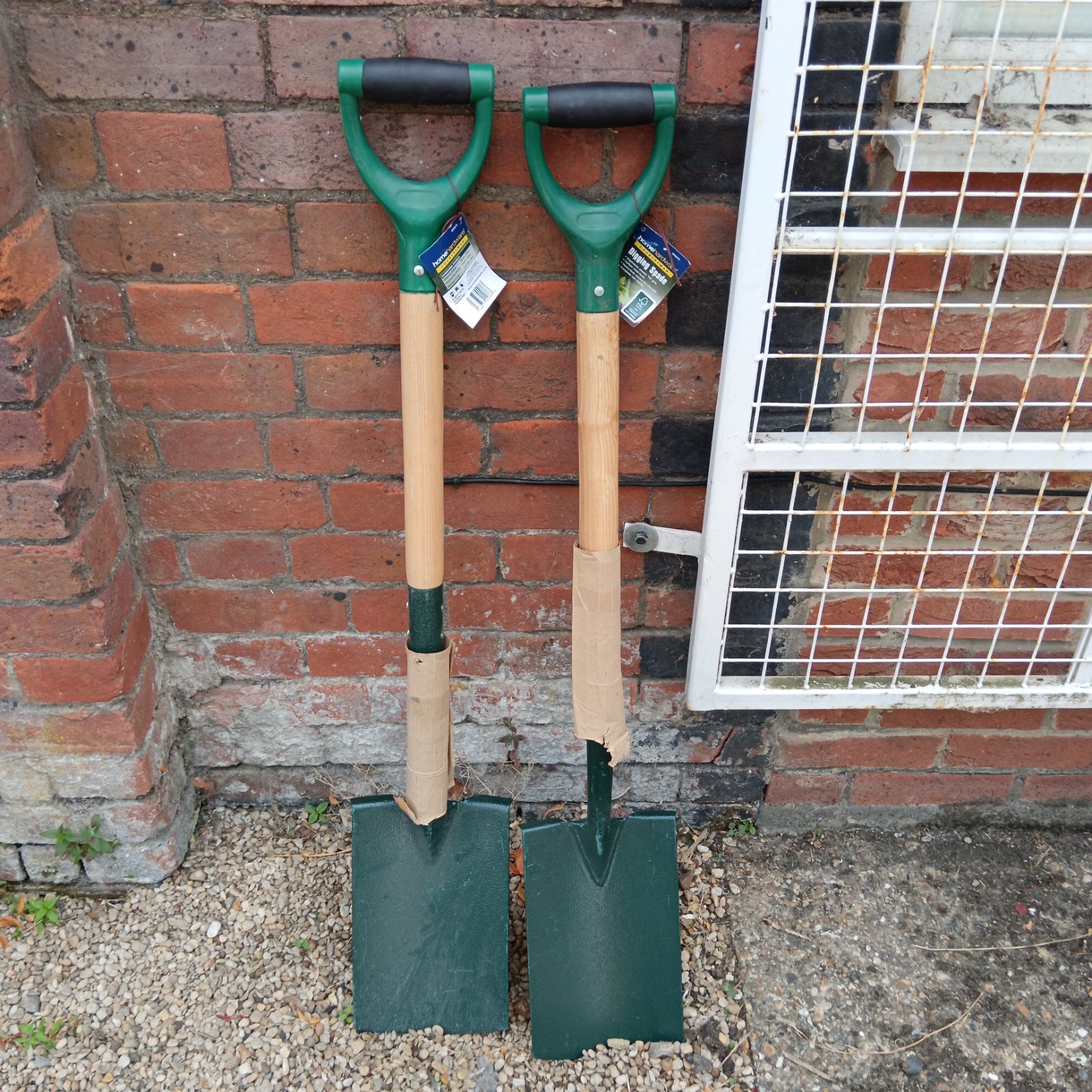 Two Home Hardware digging spades with green blades and wooden handles.