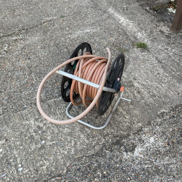 Portable hose reel in a garden setting, ideal for hose storage.