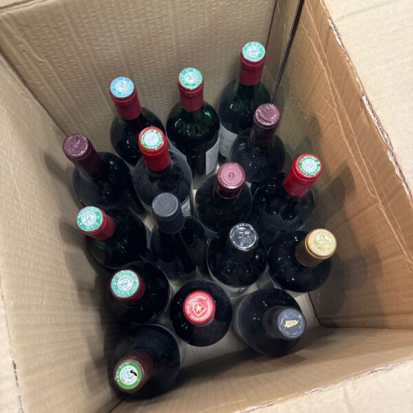 Assorted house clearance wine bottles in a cardboard box.