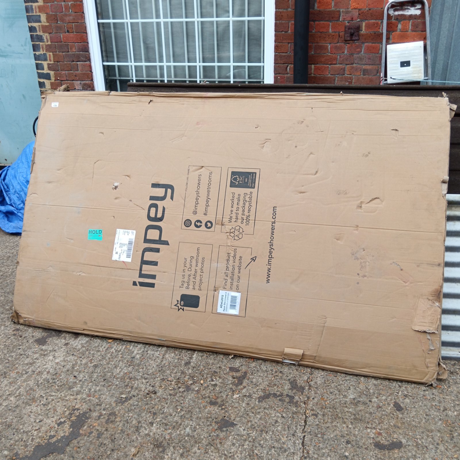 Impey shower tray in cardboard packaging, ready for installation.
