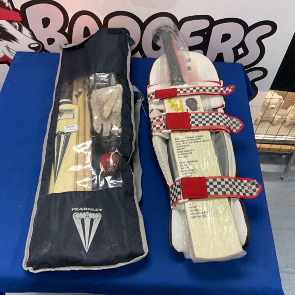 Two sets of junior cricket equipment with bats in packaging.
