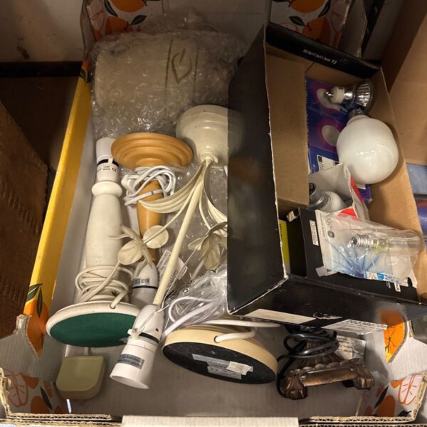 Assorted vintage lamp bases and bulbs in a cardboard box.
