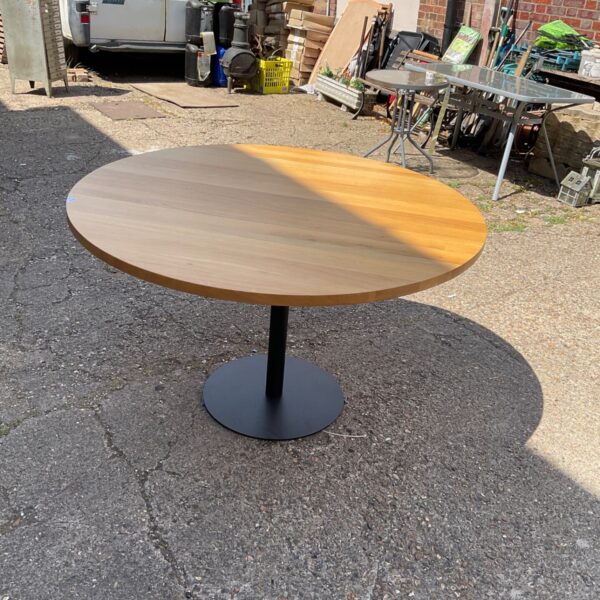 Large round office table with wooden top and black base.