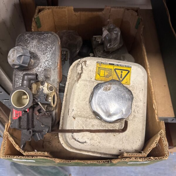 Tray of assorted used lawnmower fuel tanks for garden machinery.