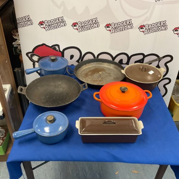 Le Creuset cast iron cookware collection on a table.