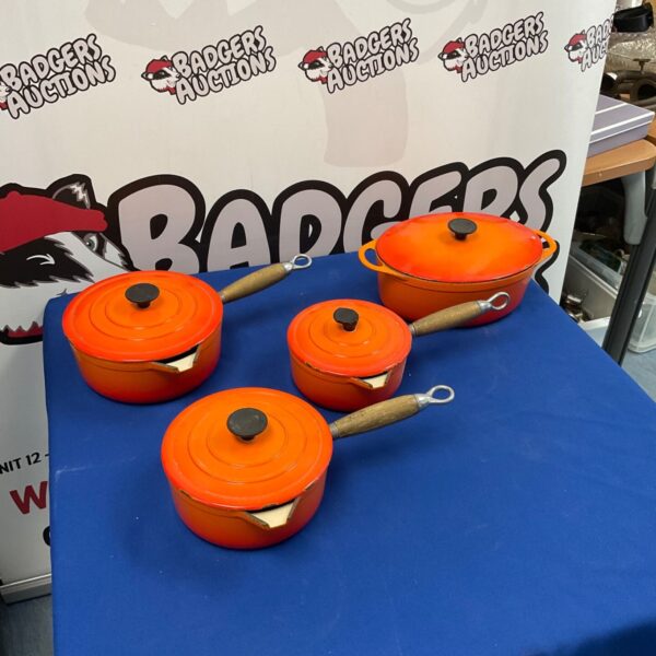 Vibrant orange Le Creuset casserole dish set on display.
