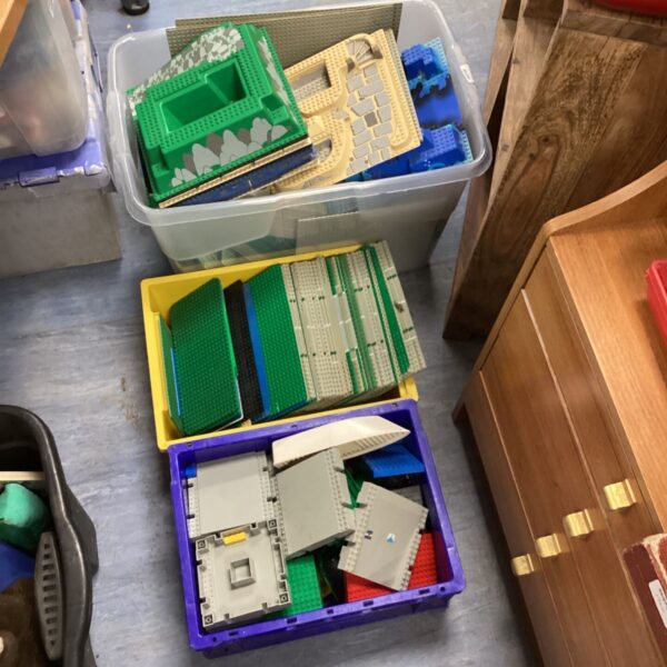 Three boxes of colourful Lego baseplates and ground boards.