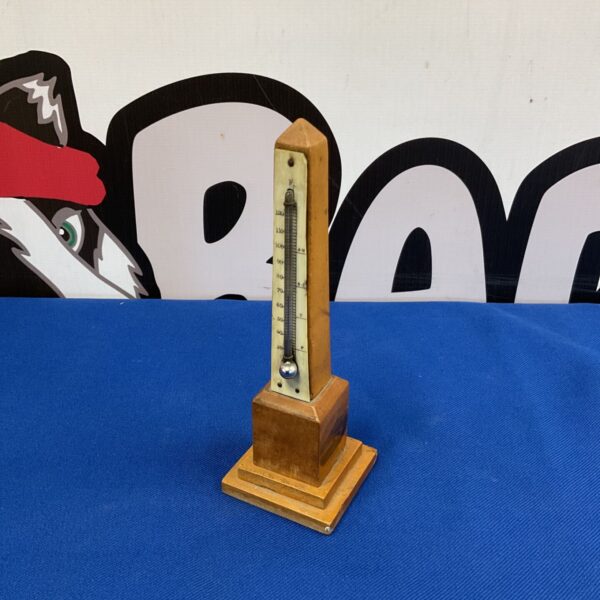 Antique Llandudno mercury thermometer on a blue surface.