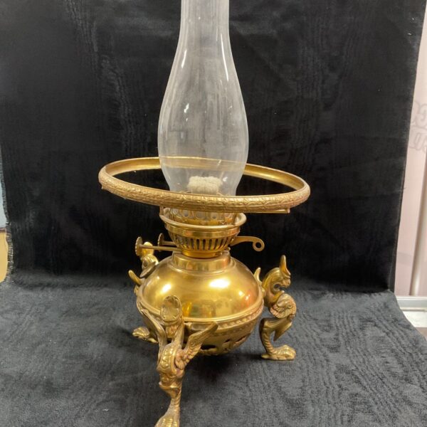 Antique brass duplex lamp featuring winged mythalogical creatures on base in egyptian revival or art nouveau style