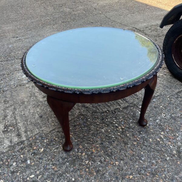 Vintage mahogany coffee table with glass top and claw feet.