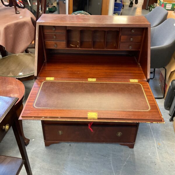 Vintage mahogany writing desk with open drawers and writing surface.