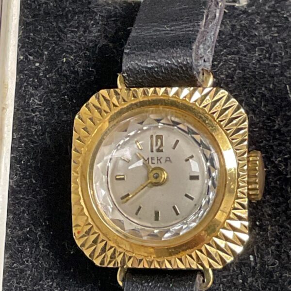 Vintage Meka ladies watch with gold square case and black strap.