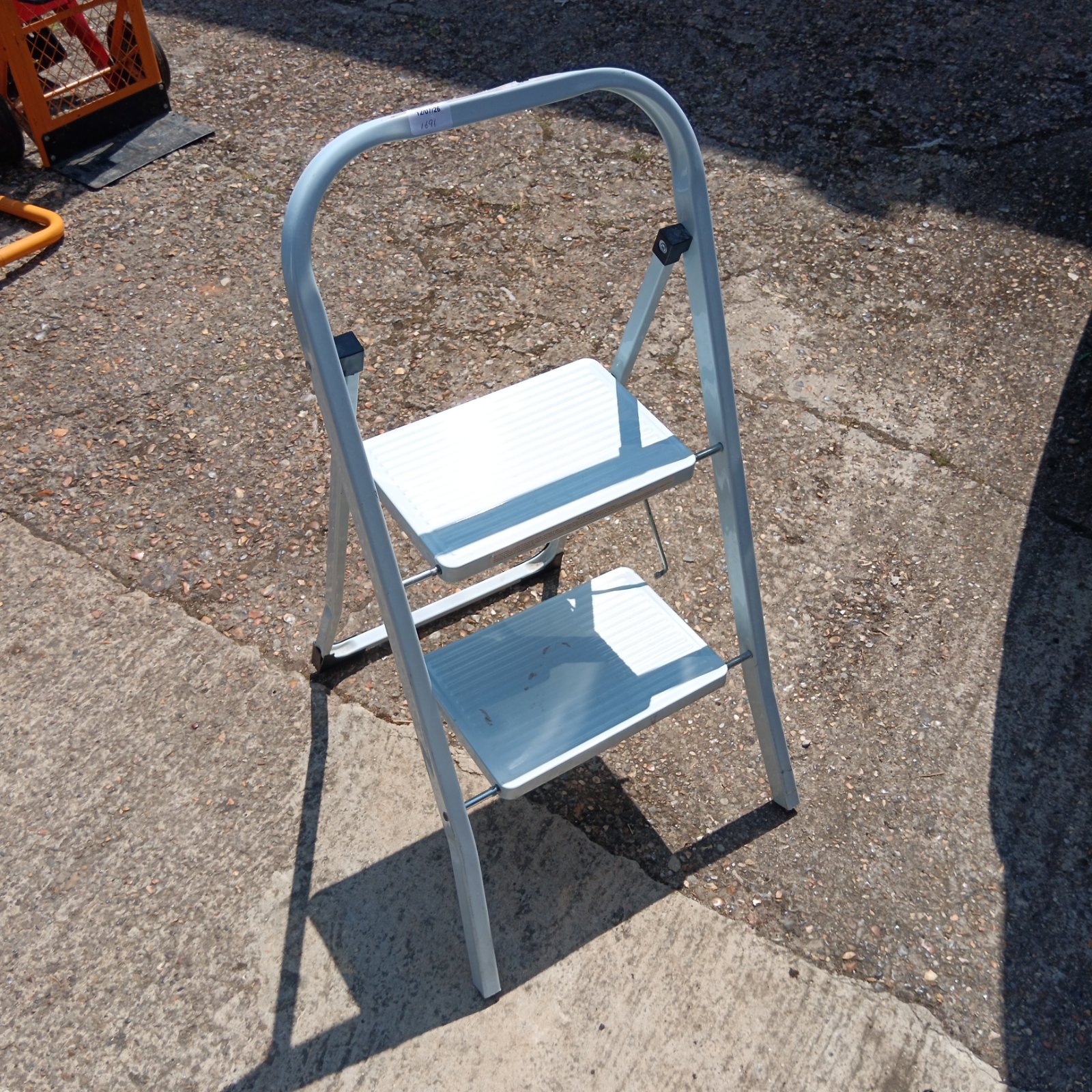 Metal folding step stool with two steps for household use.