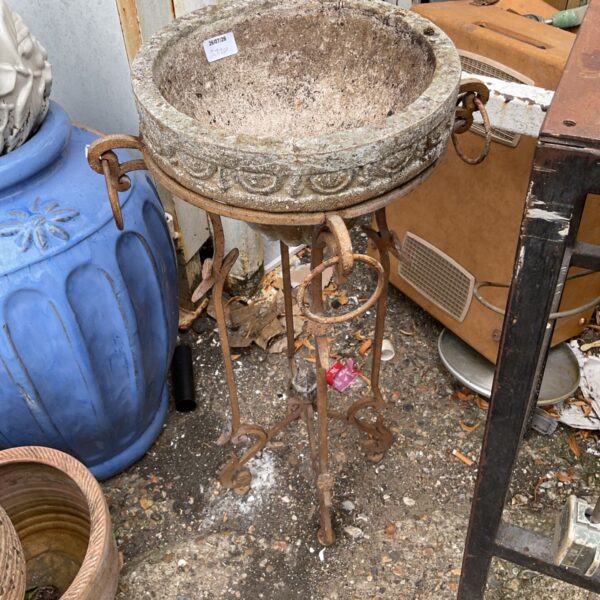Vintage metal plant stand with weathered bowl planter for garden display.