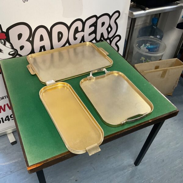 Three vintage metal trays in gold and silver tones.