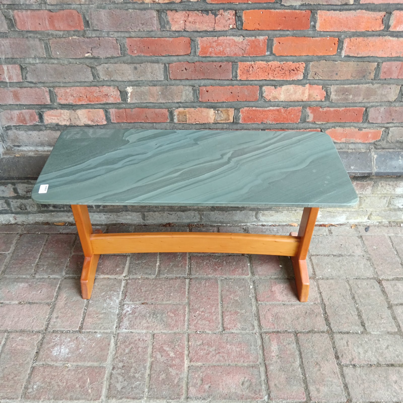 Mid-century coffee table with a green slate top and wooden legs.