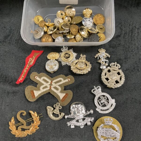 Collection of vintage British military cap badges and buttons.