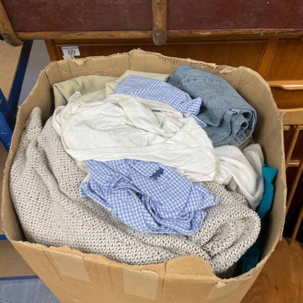 Box of mixed clothing lot with shirts and sweaters visible.