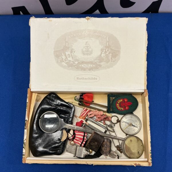 Vintage cigar box filled with mixed curios and scouting badges.