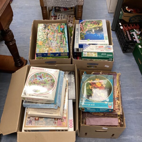 Mixed lot of jigsaw puzzles in cardboard boxes, ideal for family fun.