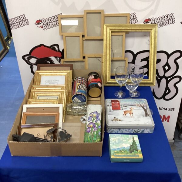 Mixed lot of photo frames, wine glasses and vintage tins on display.