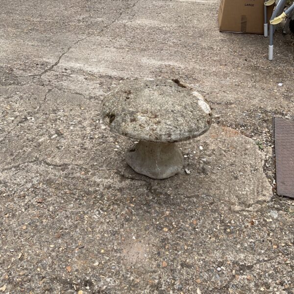 Vintage stone mushroom garden ornament in an outdoor setting.