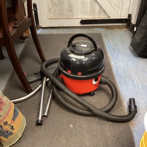 Red Numatic Henry vacuum cleaner with hose and attachments.