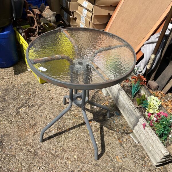 Circular patio table with glass top and metal frame.