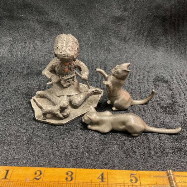 Vintage pewter figures of a girl knitting with cats playing.
