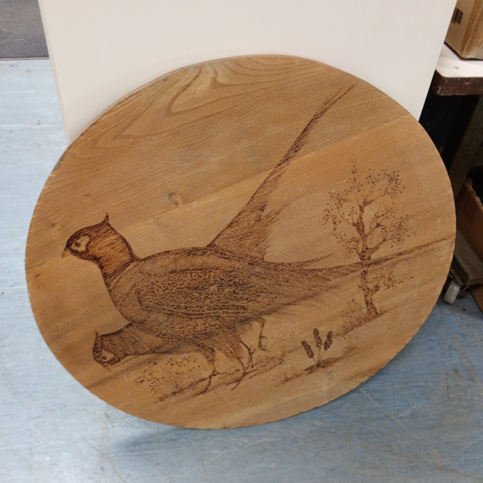Detailed pheasant engraving on a rustic wood panel.