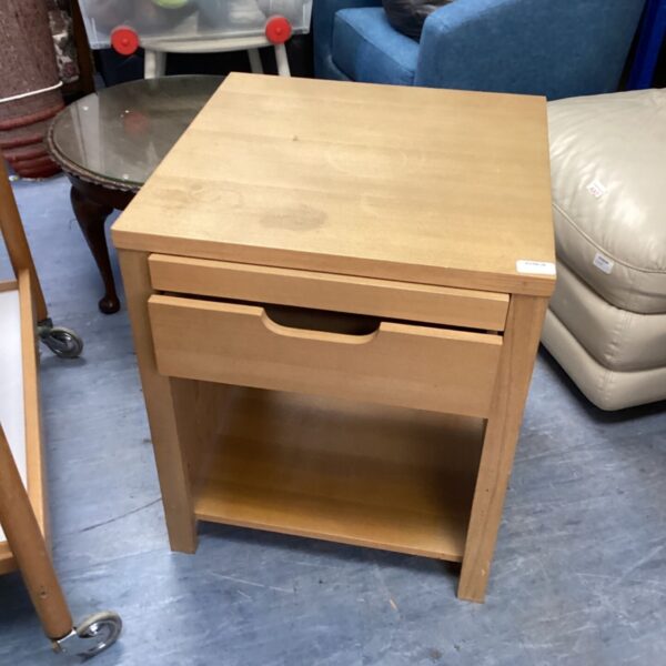 Simple pine bedside unit with a single drawer, ideal for bedroom storage.