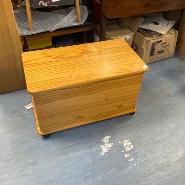 Wooden pine toy box with hinged lid and castors.
