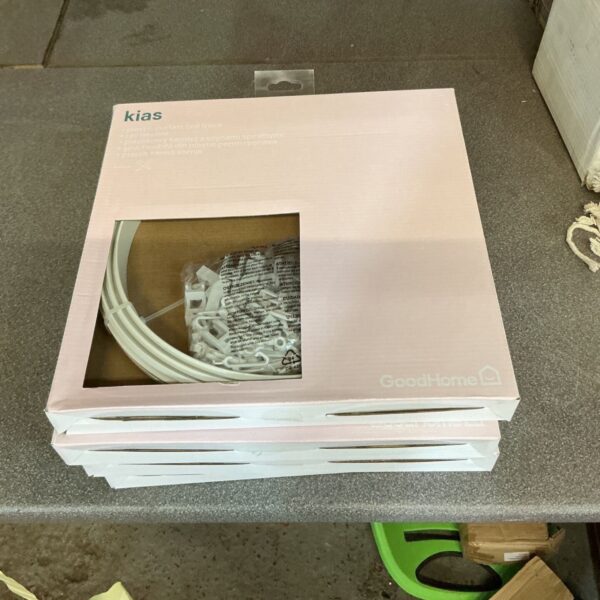 Four packs of unopened plastic curtain coil racks for window treatments.