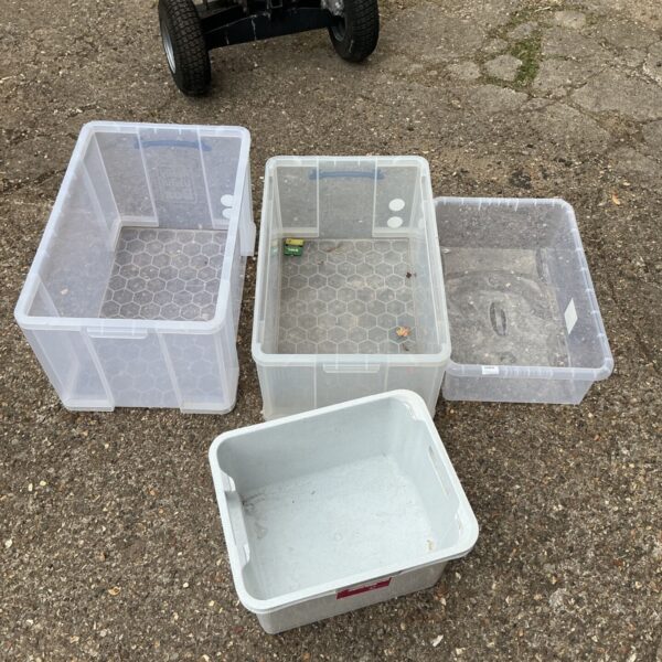 Lot of four plastic storage boxes without lids for home organization.
