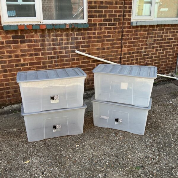 Lot of four plastic storage boxes for household organisation.