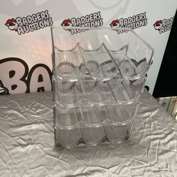Clear plastic tiered wine rack for bottle storage and display.