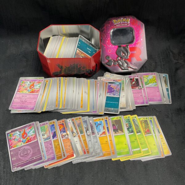 Colourful Pokemon card tin filled with assorted trading cards.
