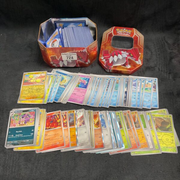 Assorted Pokemon cards inside a metal Pokemon card tin.