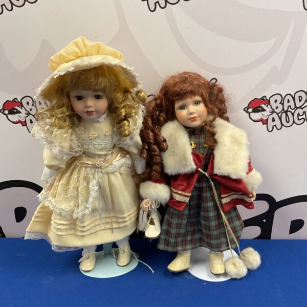 Pair of vintage porcelain collector dolls in detailed outfits.