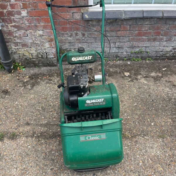 Green Qualcast Classic 35S cylinder lawn mower in a garden setting.