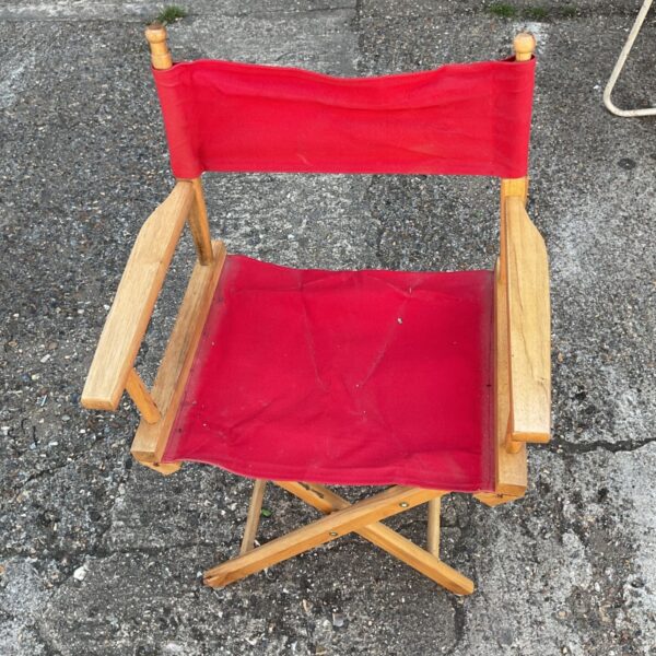 Vintage red folding campaign chair with wooden frame.