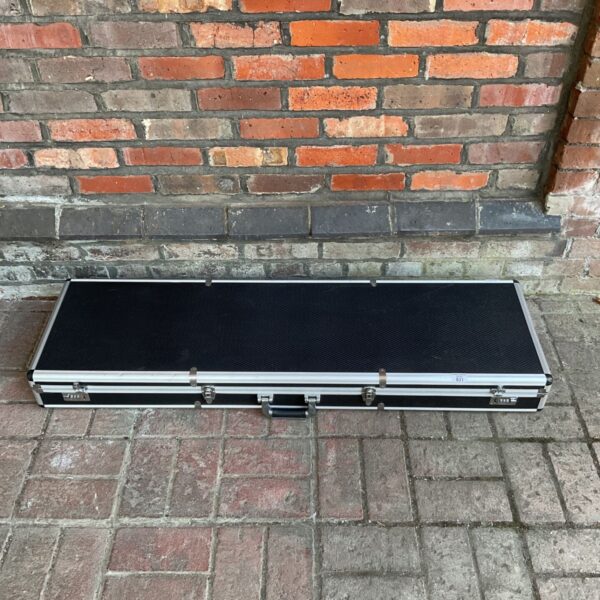 Large aluminium rifle case with locking clasps against a brick wall.